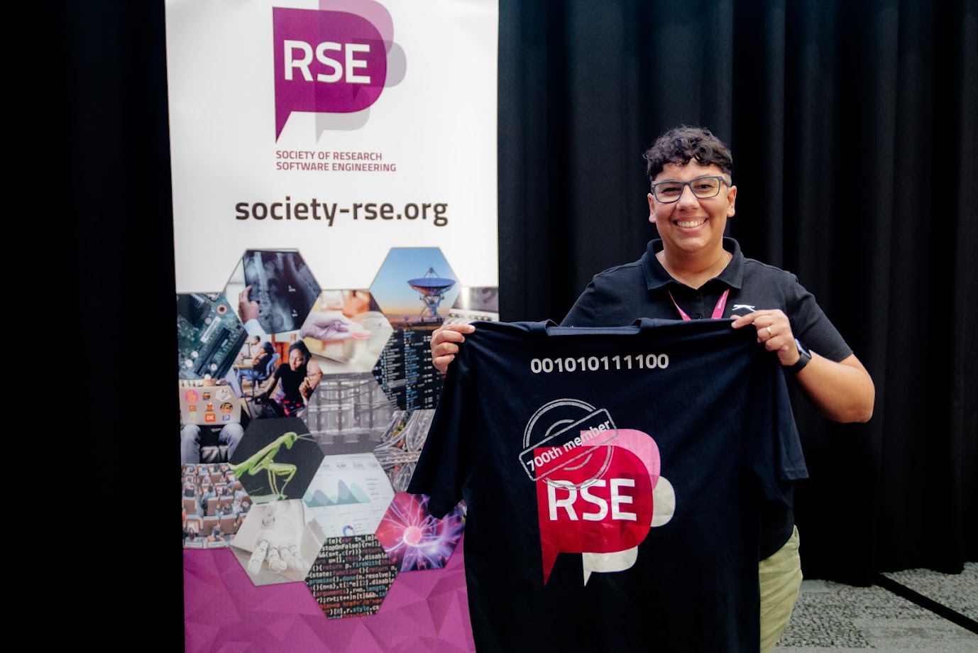 A photo of Patricia Ternes holding up a t-shirt, celebrating the 700th member of the Society. The t-shirt has the RSE Society logo, "700th Member" and the number 700 written in binary on the back.