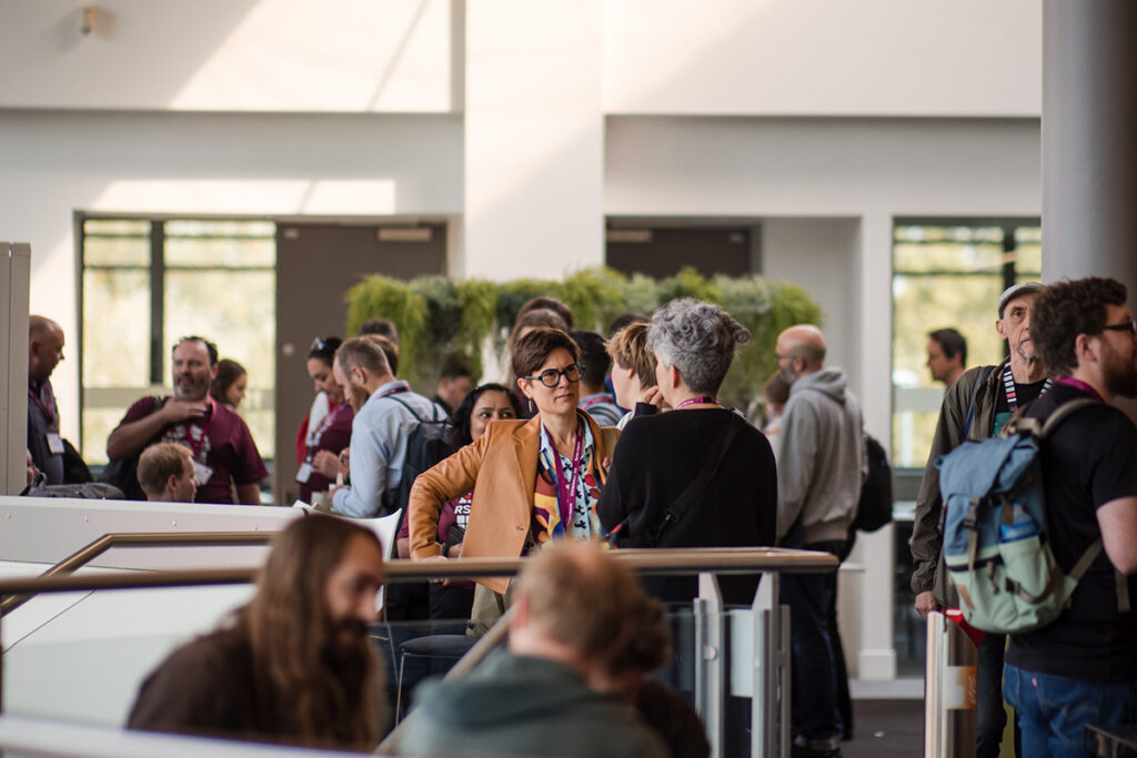 Several groups of people standing or sitting and chatting during the leaders meeting at RSECon25.